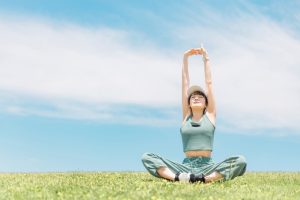 青空の下で伸びをする女性